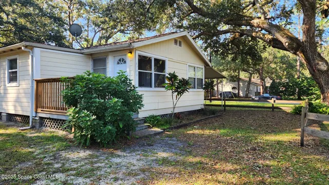 a view of a yard in front of a house with large trees