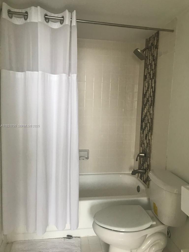770 Claughton Island Drive, Unit 1404 Miami, FL 33131 - Photo 4 of 23 a bathroom with a shower curtain and a toilet