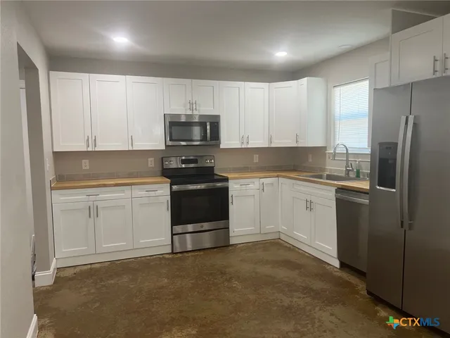 a kitchen with white cabinets and stainless steel appliances