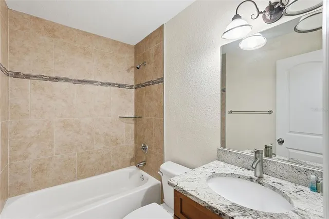 a bathroom with a granite countertop sink a toilet and mirror