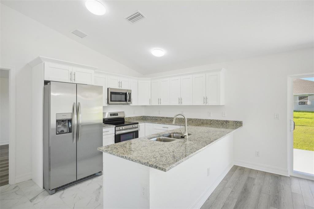 11145 2nd Avenue Punta Gorda, FL 33955 - Photo 2 of 9 a kitchen with stainless steel appliances granite countertop a sink and a refrigerator