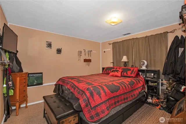 a bedroom with a bed and a flat tv screen on dresser