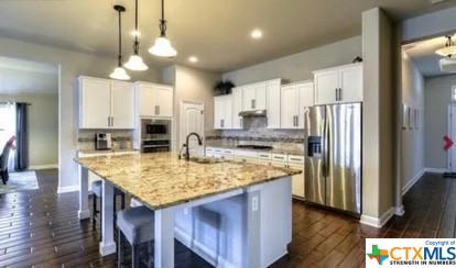 a kitchen with stainless steel appliances granite countertop a kitchen island and a refrigerator