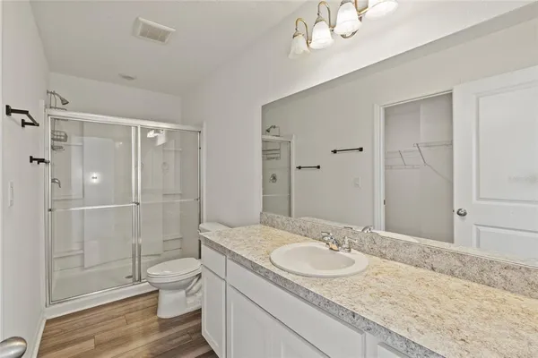 a bathroom with a granite countertop sink a toilet a mirror and shower