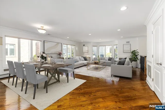 a living room with couches a coffee table and kitchen view with wooden floor