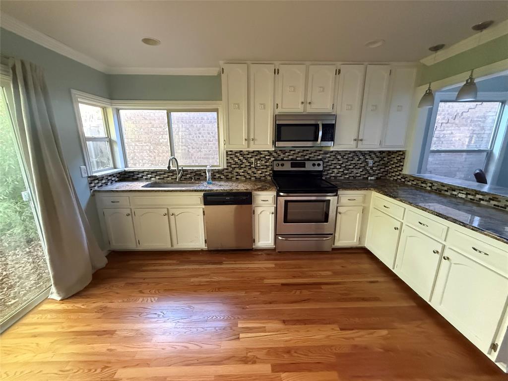 4139 Rosser Square Dallas, TX 75244 - Photo 5 of 7 a kitchen with stainless steel appliances a stove a sink and white cabinets