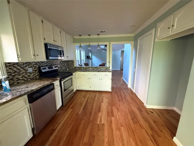 a kitchen with wooden floors and stainless steel appliances