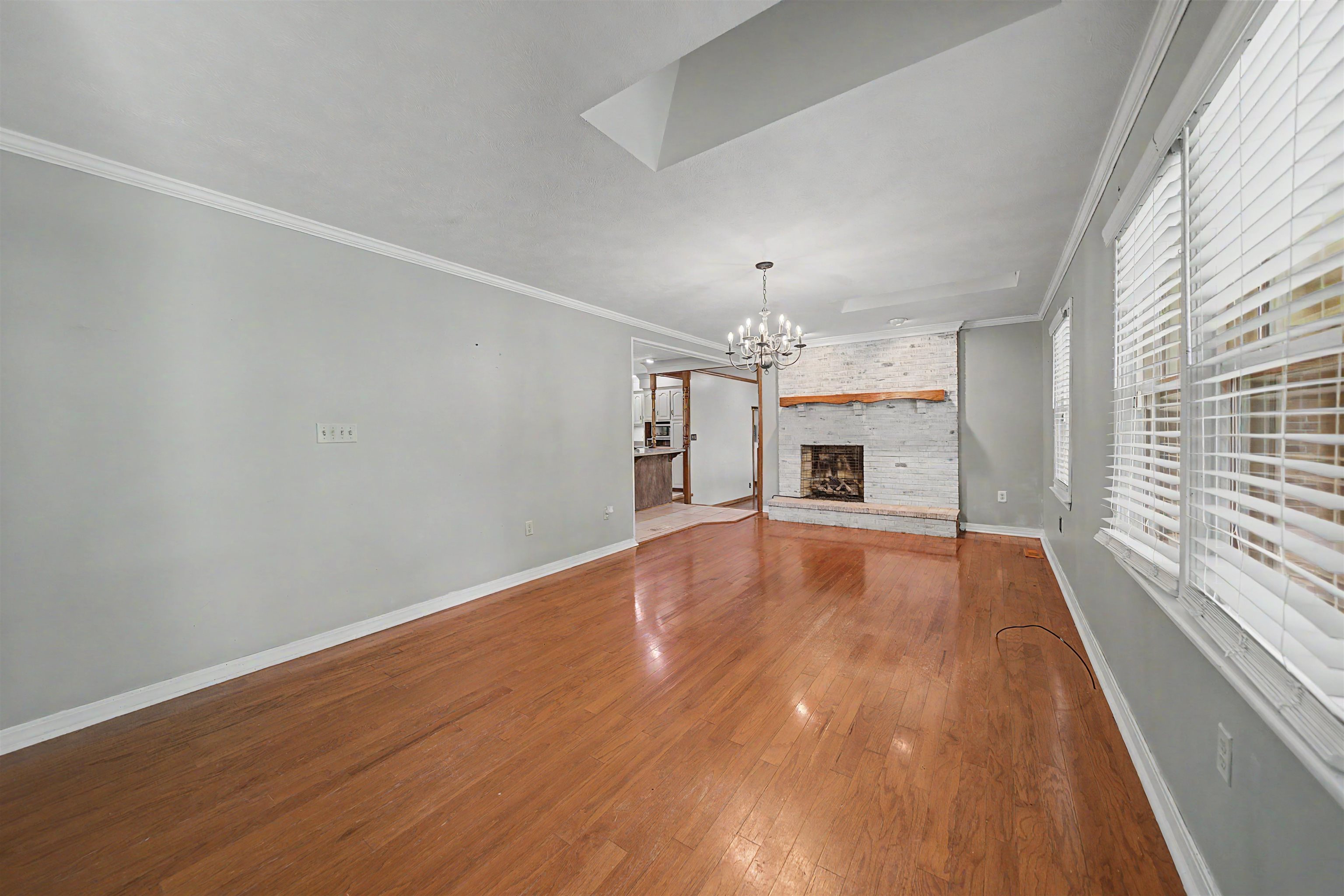 436 Skyline Road Selmer, TN 38375 - Photo 39 of 40 Spacious interior featuring wood-finish flooring, a brick fireplace with a wood mantel, crown molding, and a tray ceiling