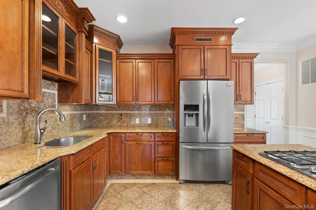 a kitchen with stainless steel appliances granite countertop a refrigerator a stove and a sink with wooden cabinets