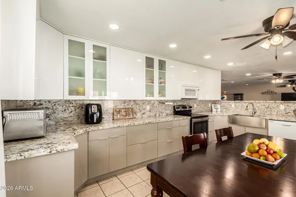 a kitchen with stainless steel appliances granite countertop a dining table chairs refrigerator and cabinets