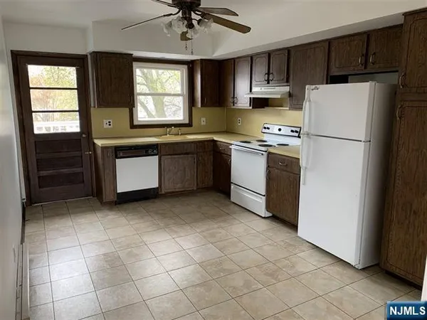 a kitchen with granite countertop a refrigerator a sink a microwave and cabinets