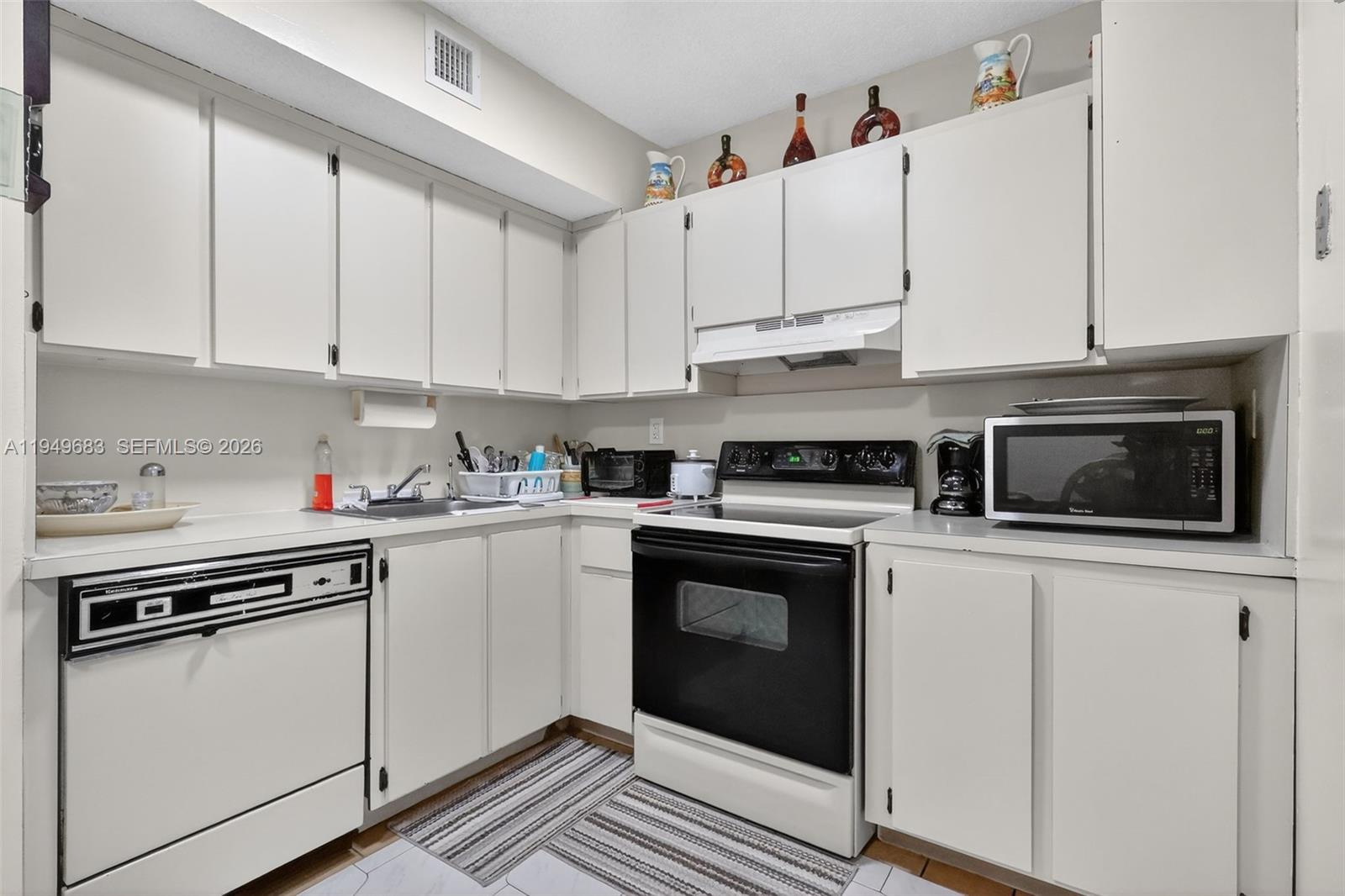 2224 West 53rd Place, Unit 2224 Hialeah, FL 33016 - Photo 12 of 27 a kitchen with stainless steel appliances granite countertop a stove and white cabinets