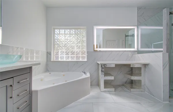 a spacious bathroom with a granite countertop sink mirror and bathtub