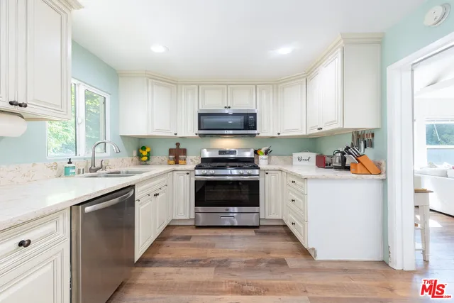 a kitchen with granite countertop a stove top oven a sink dishwasher and a refrigerator with wooden floor