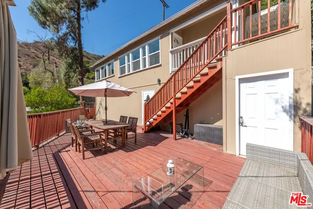 a view of a house with wooden deck stairs and furniture
