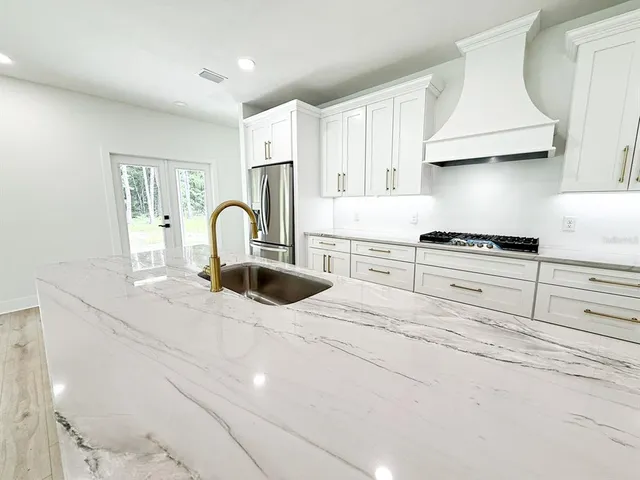 a kitchen with granite countertop white cabinets and stainless steel appliances