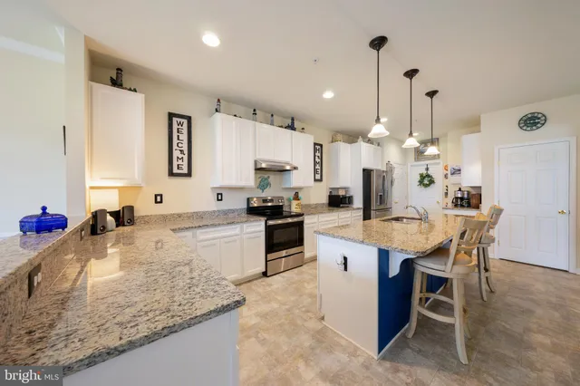 a kitchen with stainless steel appliances granite countertop a refrigerator a sink a stove a dining table and chairs