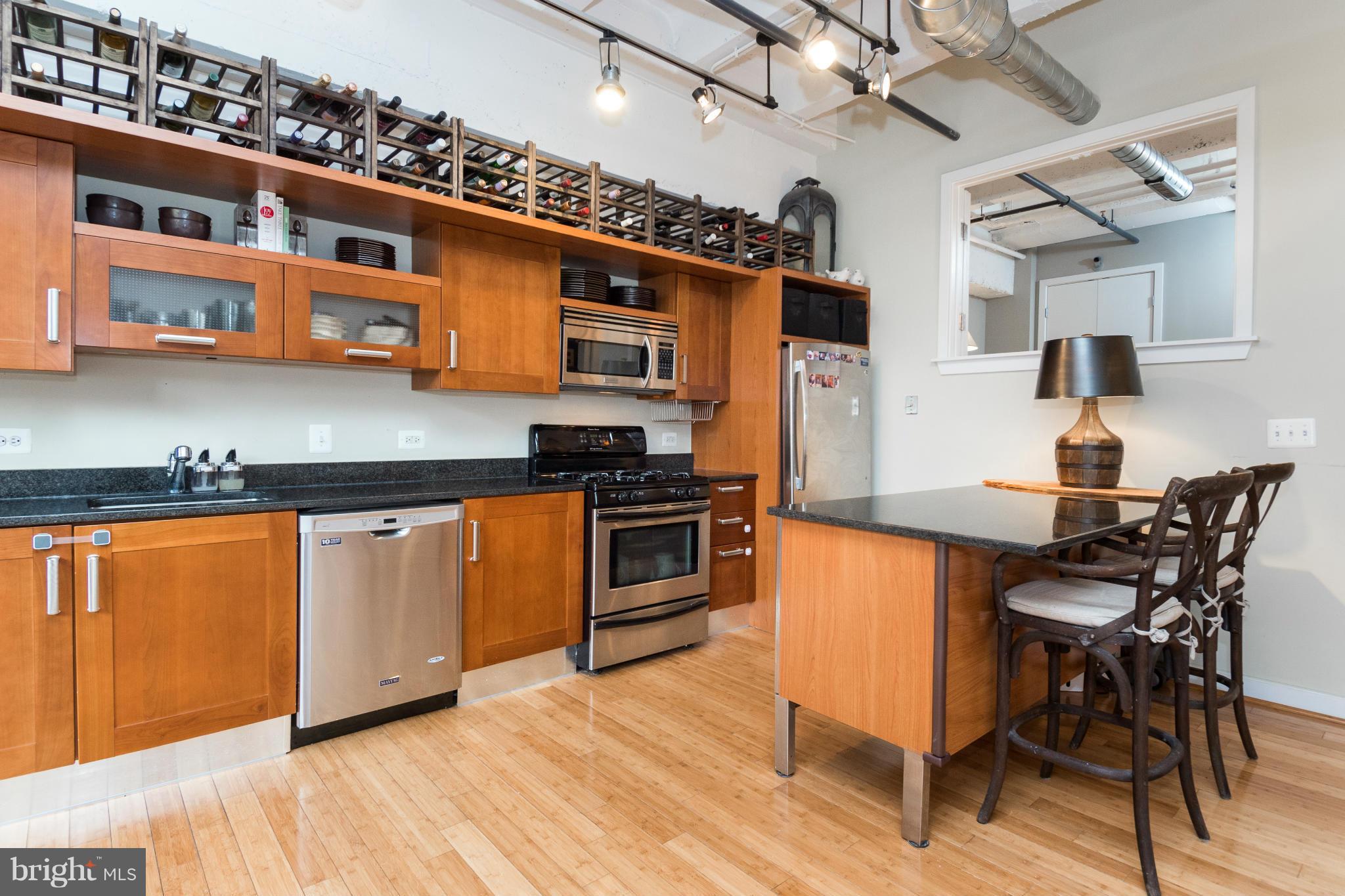 1401 Church Street Northwest, Unit 306 Washington, DC 20005 - Photo 11 of 18 a kitchen with stainless steel appliances granite countertop a stove top oven a sink a dining table and chairs with wooden floor