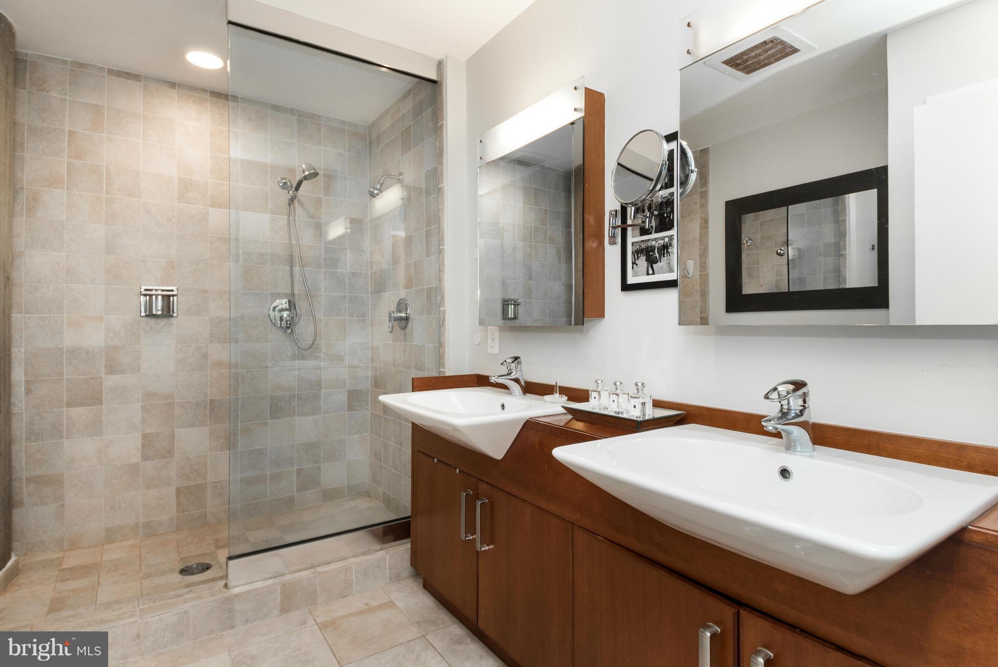 1401 Church Street Northwest, Unit 306 Washington, DC 20005 - Photo 13 of 18 a bathroom with a sink a mirror a shower and vanity