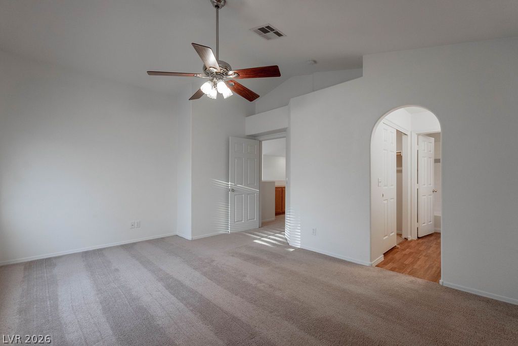 8379 Rockefeller Street Las Vegas, NV 89123 - Photo 21 of 36 A spacious bedroom features soft carpeting, high vaulted ceilings, and an elegant arched doorway.