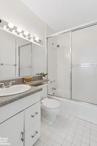 a bathroom with a granite countertop sink a toilet a mirror and shower