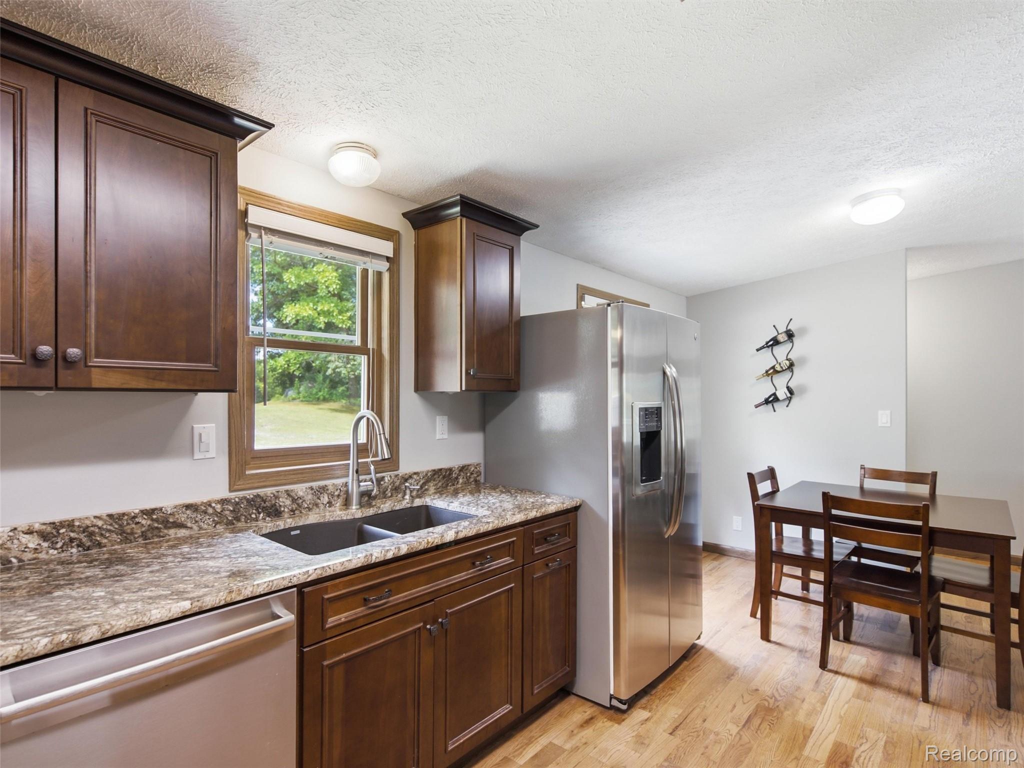 5003 Mason Road Howell, MI 48843 - Photo 15 of 59 Kitchen featuring rich wood cabinetry, patterned countertops, a stainless steel refrigerator, and wood-finish flooring