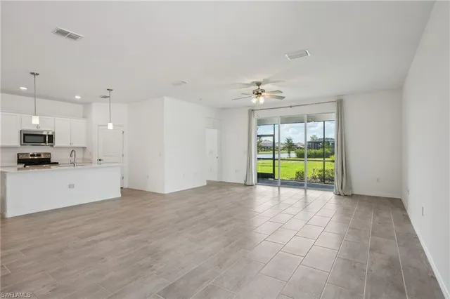 a view of an empty room with a kitchen view and a window
