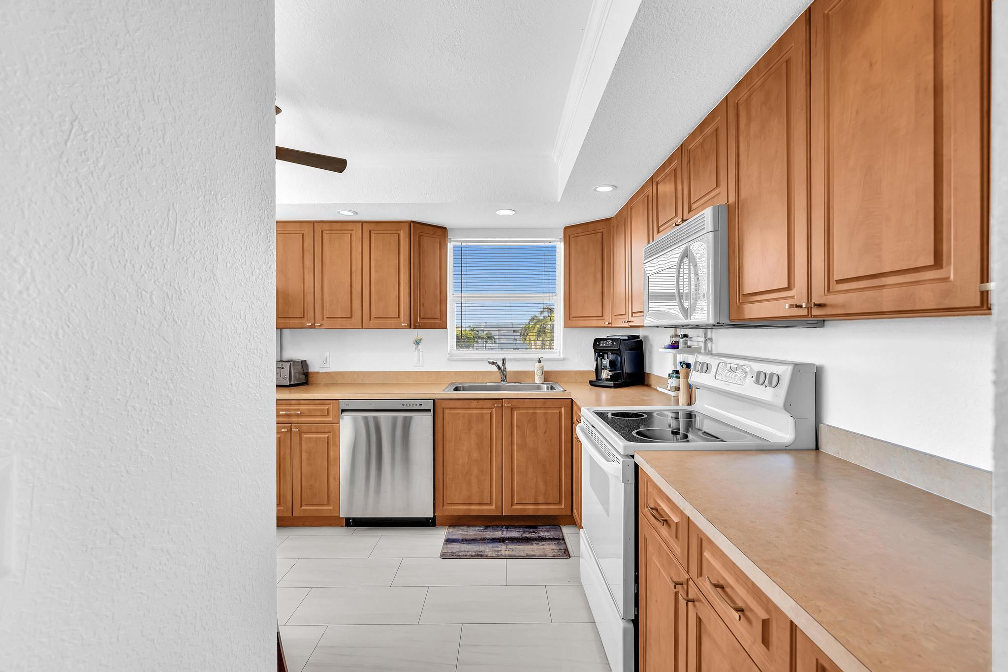 3 Colonial Club Drive, Unit 300 Boynton Beach, FL 33435 - Photo 12 of 71 a kitchen with stainless steel appliances granite countertop a stove a sink and a microwave