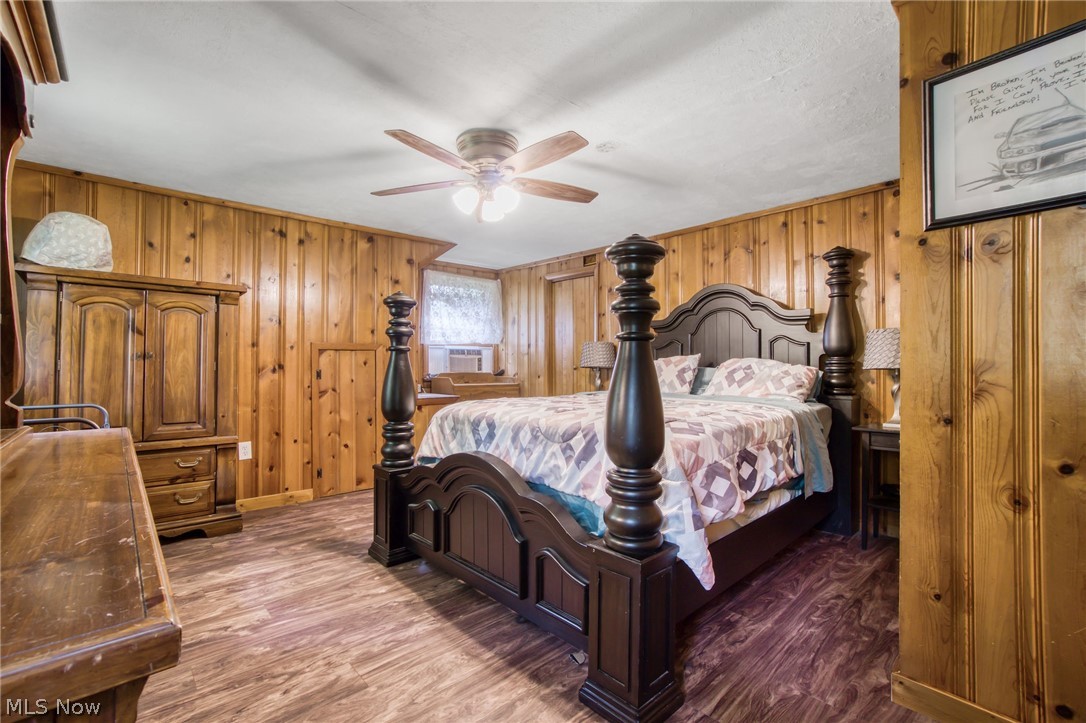 15221 Thompson Road Thompson, OH 44086 - Photo 18 of 31 Bedroom featuring wood walls, ceiling fan, and dark hardwood / wood-style floors