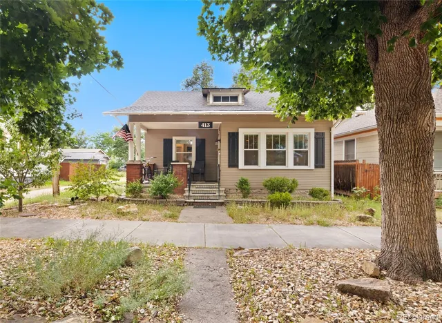 a front view of a house with a yard outdoor seating and covered with trees