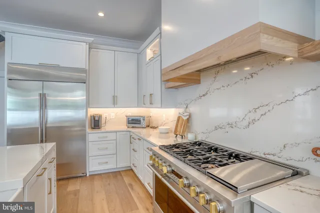 a kitchen with stainless steel appliances granite countertop a stove top oven a sink a dining table and chairs