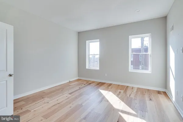 a view of an empty room and closet with wooden floor