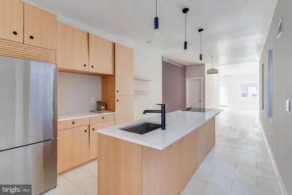 a view of a kitchen with a refrigerator a kitchen island wooden floor and windows