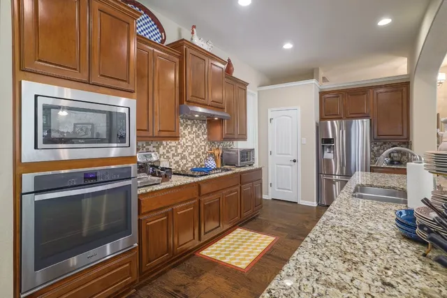 a large kitchen with stainless steel appliances granite countertop a stove and cabinets