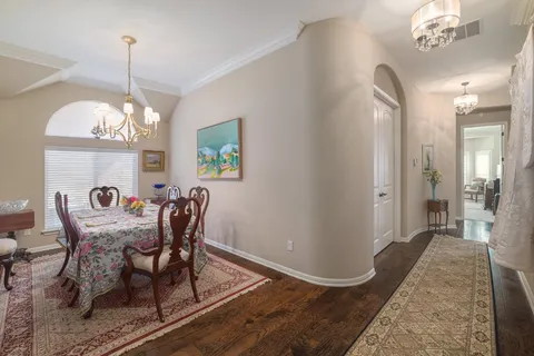 a dining room with chandelier and wooden floor