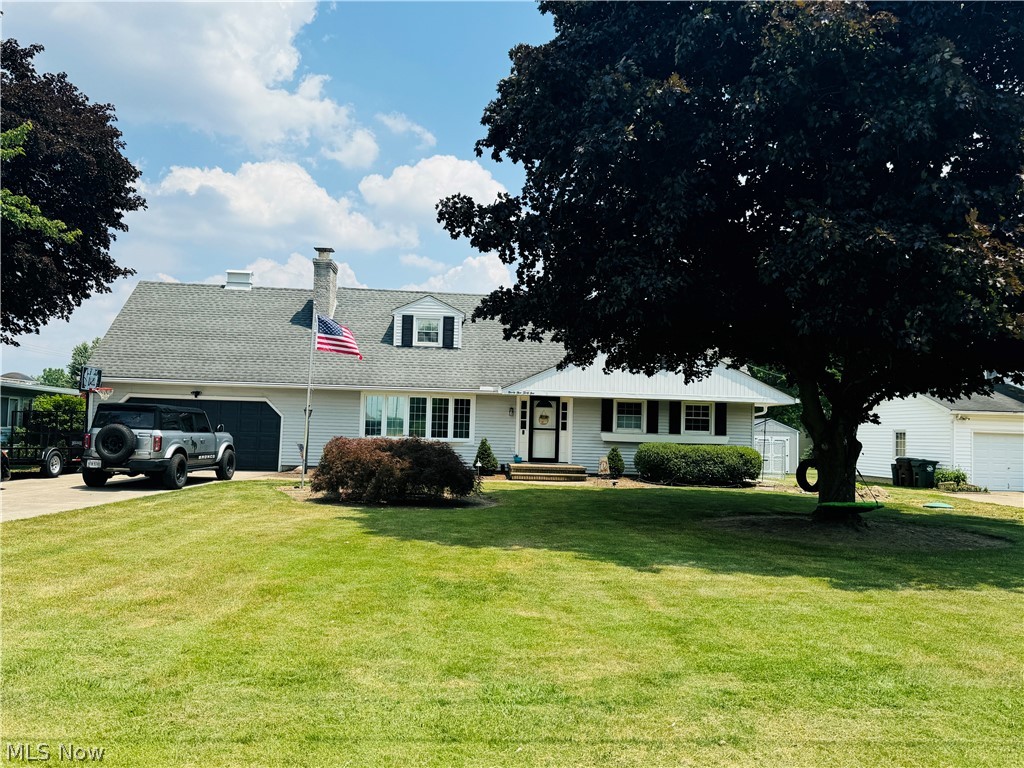 Cape cod home featuring a front yard and a garage