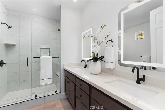 a spacious bathroom with a double vanity sink a large mirror and shower