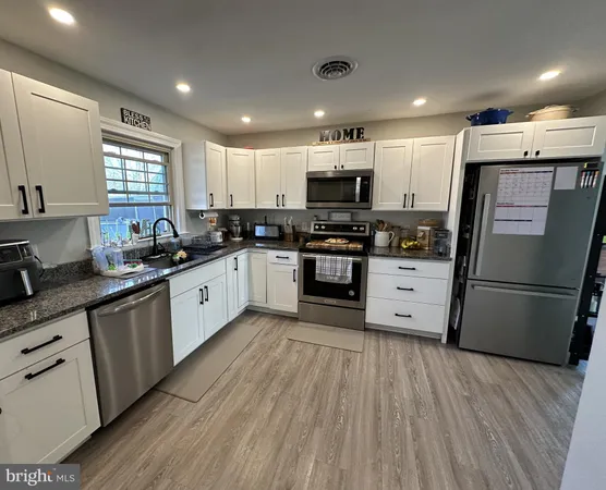 a kitchen with stainless steel appliances a refrigerator a sink a stove a microwave a center island and a window