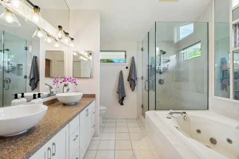a bathroom with a granite countertop tub sink and mirror