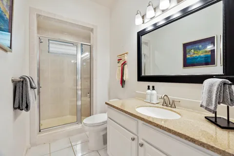 a bathroom with a granite countertop sink a toilet a mirror and shower