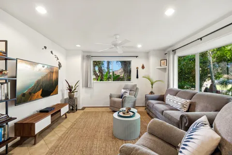 a living room with furniture a flat screen tv and a large window