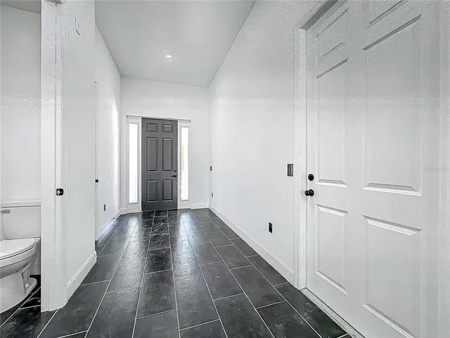 a view of a hallway with wooden floor and a bathroom