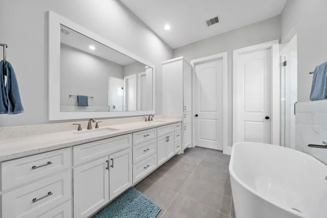 a spacious bathroom with a double vanity sink a mirror a bathtub and