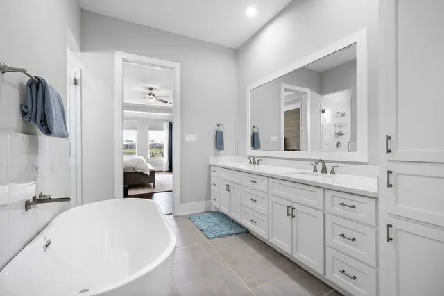 a spacious bathroom with a double vanity sink mirror and bathtub