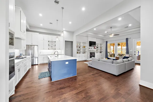 a large white kitchen with stainless steel appliances kitchen island a large counter top and a couch