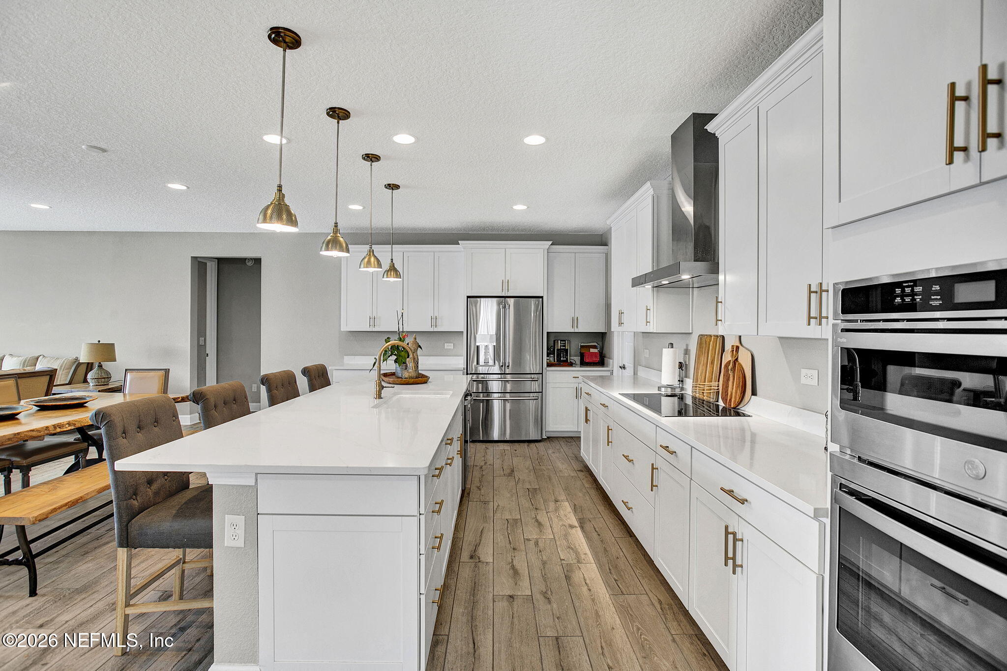 85401 Fall River Parkway Fernandina Beach, FL 32034 - Photo 4 of 38 a large kitchen with kitchen island a stove a sink a refrigerator and a dining table with wooden floor