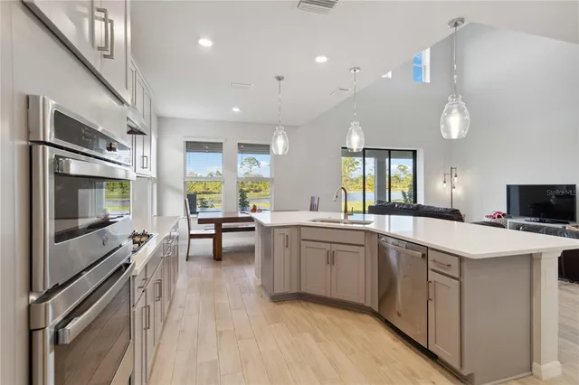 a kitchen with stainless steel appliances a sink a stove a refrigerator cabinets and living room view