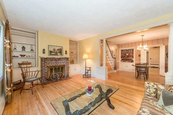 a living room with furniture a fireplace and a dining table with wooden floor
