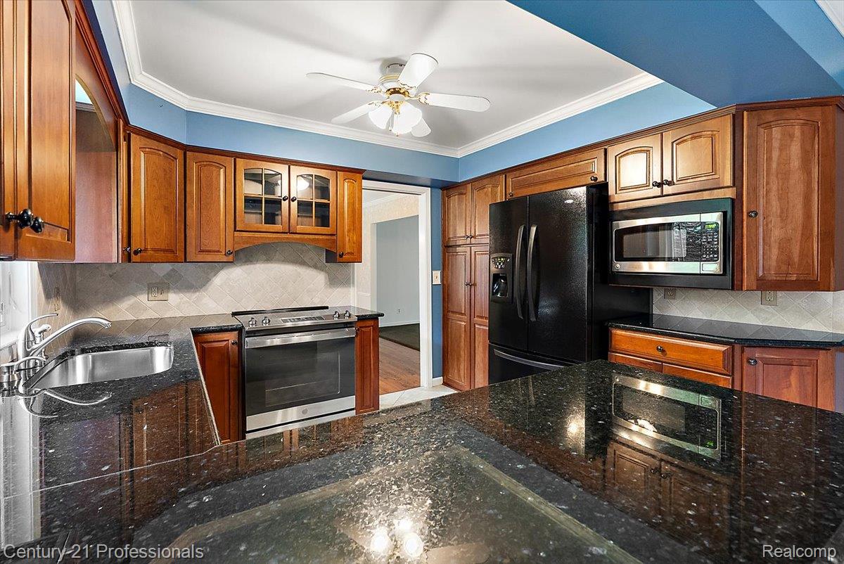 633 Foxhall Road Bloomfield Hills, MI 48304 - Photo 34 of 61 Kitchen with dark granite countertops, wood cabinetry, stainless steel appliances, and a tile backsplash