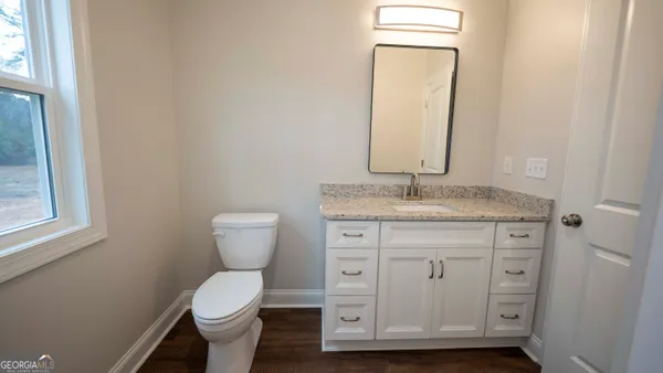 a bathroom with a granite countertop toilet sink and mirror